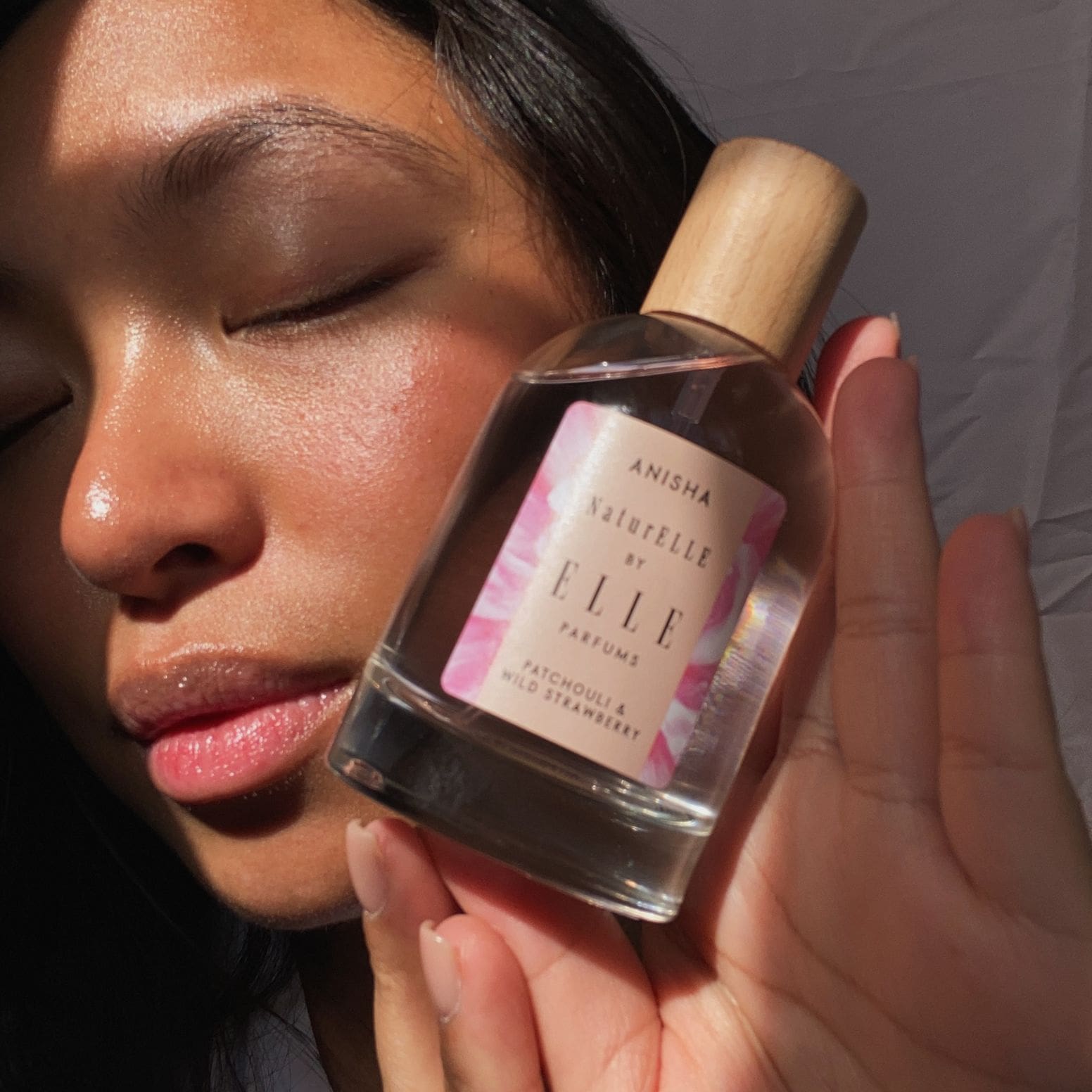 Image of a female model holding NaturELLE Anisha by ELLE Parfums 100ml. The main ingredients in Anisha Eau De Parfum are Patchouli & Wild Strawberry. It's vegan, cruelty-free, naturally and ethically sourced. It's perfect for day and night.