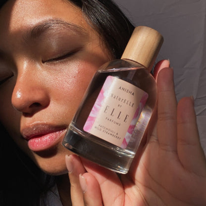 Image of a female model holding NaturELLE Anisha by ELLE Parfums 100ml. The main ingredients in Anisha Eau De Parfum are Patchouli & Wild Strawberry. It's vegan, cruelty-free, naturally and ethically sourced. It's perfect for day and night.